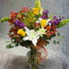 A lush autumn arrangement featuring lilies , roses and seasonal blooms in