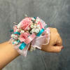 Pink rose wrist corsage with white filler flowers and ribbon on a wrist