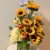 Sunflower arrangement in a glass vase with white hydrangea and small pumpkins