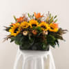 Sunflowers and orange lilies arranged in a rectangular vase