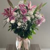 Pink lilies and roses in a glass vase with a ribbon