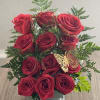 Red roses arranged in a clear square vase with fern accents