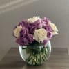 Purple and white roses in a round glass vase
