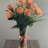 Peach roses in a clear glass vase with a pink ribbon