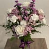 Pink and white bouquet in a glass vase with a purple ribbon