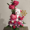 Pink rose arrangement with a teddy bear and flowers in a glass vase
