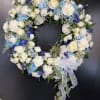 Heart-shaped floral wreath with white and blue flowers and a sheer ribbon
