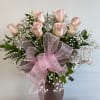 Pink roses and baby's breath in a mauve vase with a large pink bow