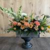 Mixed floral arrangement in a dark wooden container on a pedestal stand