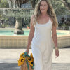 Woman in a white dress holding a wicker basket of sunflowers