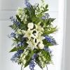 Standing floral spray with white lilies, white roses, and blue flowers