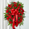 Red roses and carnations in a standing spray with a large red bow