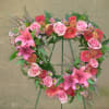 Heart-shaped floral wreath with pink roses and lilies on a stand