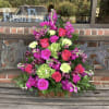Pink and magenta floral arrangement in a wooden basket