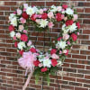 Heart-shaped floral wreath with pink and white flowers on a stand