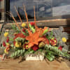 Orange lily and mixed flowers in a cream container