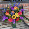 Colorful mixed bouquet in a glass vase with roses, gerbera daisies, and poppies