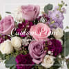 Handheld bouquet of pink, lavender, and white roses with purple accents