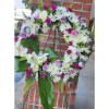 Circular floral wreath on a stand with white, pink, and lavender flowers
