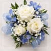 White roses with blue flowers and ribbon in a compact bouquet