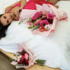Woman in pink dress lying beside two pink flower bouquets