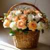 Basket of peach and white roses with greenery