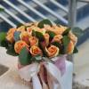 Peach roses arranged in a pink hat box with a ribbon bow