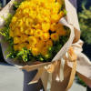 Large bouquet of yellow roses wrapped in beige paper with ribbon