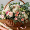 Basket of pink and white roses with eucalyptus and ribbon rolls