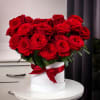 Red roses arranged in a white hat box with a red ribbon