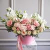 Pink and white floral arrangement in a pink hat box with ribbon