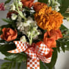 Orange roses and marigold bouquet with white flowers and checkered ribbon