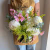 Pink and white flowers arranged in a glass vase with greenery