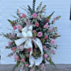 Standing floral spray with pink roses and carnations, finished with a white ribbon bow