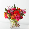 Bright mixed bouquet of roses, gerbera daisies, and carnations in a clear glass vase