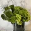 Green floral arrangement in a dark glass vase