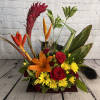 Tropical flower arrangement with red roses, orange lily, and yellow daisies in a low wooden base