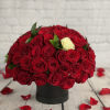 Round bouquet of red roses with one white rose in a black box