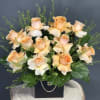 Peach roses arranged in a black box with greenery