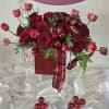 A festive Christmas flower arrangement featuring roses, surrounded by mixed flowers.