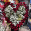 Heart-shaped red rose arrangement with white baby's breath in a black vase