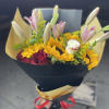 Bouquet of pink lilies, yellow sunflowers, and red roses wrapped in black paper