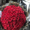 Large round bouquet of tightly packed red roses wrapped in layered black and gold paper.