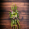 Tall floral standing spray with white, green, and purple blooms on an easel