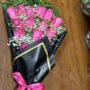 Bouquet of pink roses wrapped in black paper with a pink ribbon