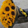 Bouquet of yellow sunflowers wrapped in black paper with a yellow ribbon