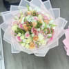 Pastel bouquet of roses and mixed blooms wrapped in translucent pink paper