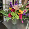 Mixed bouquet with pink roses, lilies, and purple flowers in a glass vase