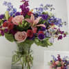 Mixed bouquet of pink, purple, and blue flowers in a clear glass vase