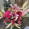 Pink lilies, gerbera daisies, and roses in a glass vase